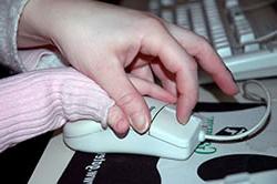 Closeup of an adult hand helping a child's hand click a mouse